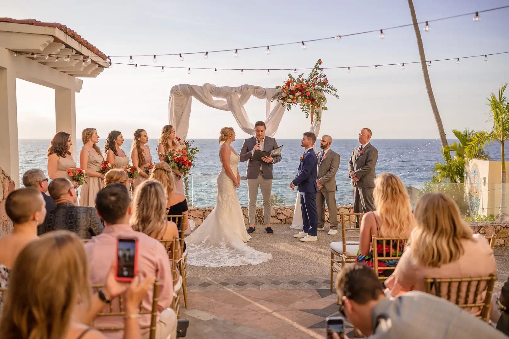 Ceremony under string lights above the ocean